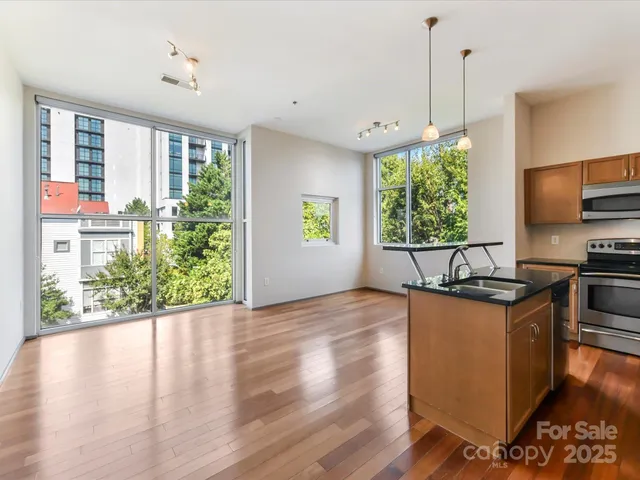 a kitchen with stainless steel appliances granite countertop a sink a stove and a wooden floors