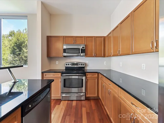 a kitchen with stainless steel appliances granite countertop a refrigerator a stove and a wooden floors