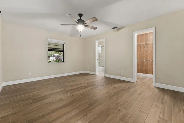 a view of an empty room with wooden floor and a window