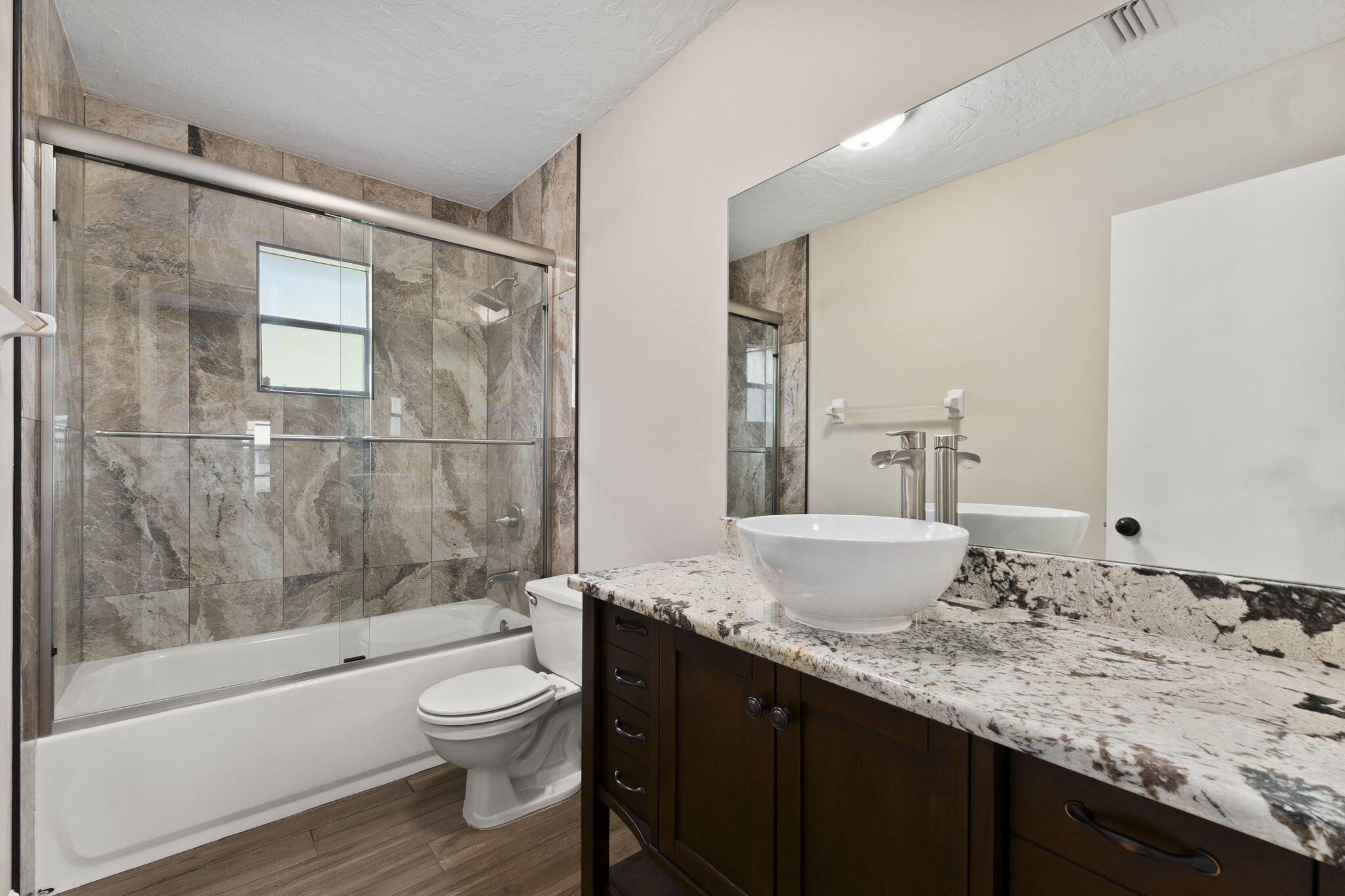 3585 Southeast 8th Street Okeechobee, FL 34974 - Photo 26 of 39 a bathroom with a granite countertop sink toilet a large mirror a bathtub and shower