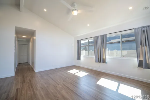 a view of an empty room with wooden floor and a window