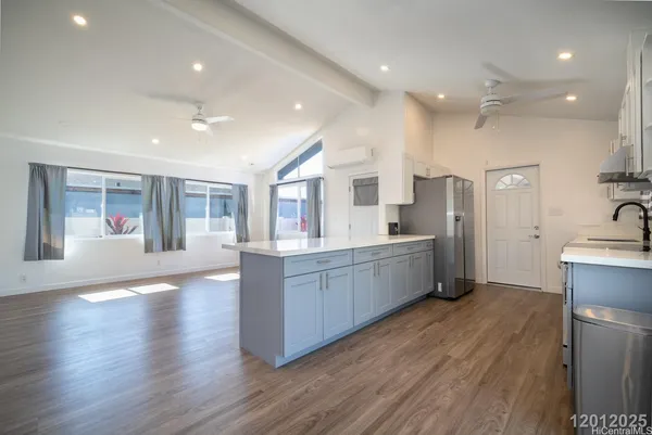 a large kitchen with stainless steel appliances a large counter top a sink and a refrigerator