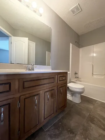 a spacious bathroom with a double vanity sink toilet and a mirror