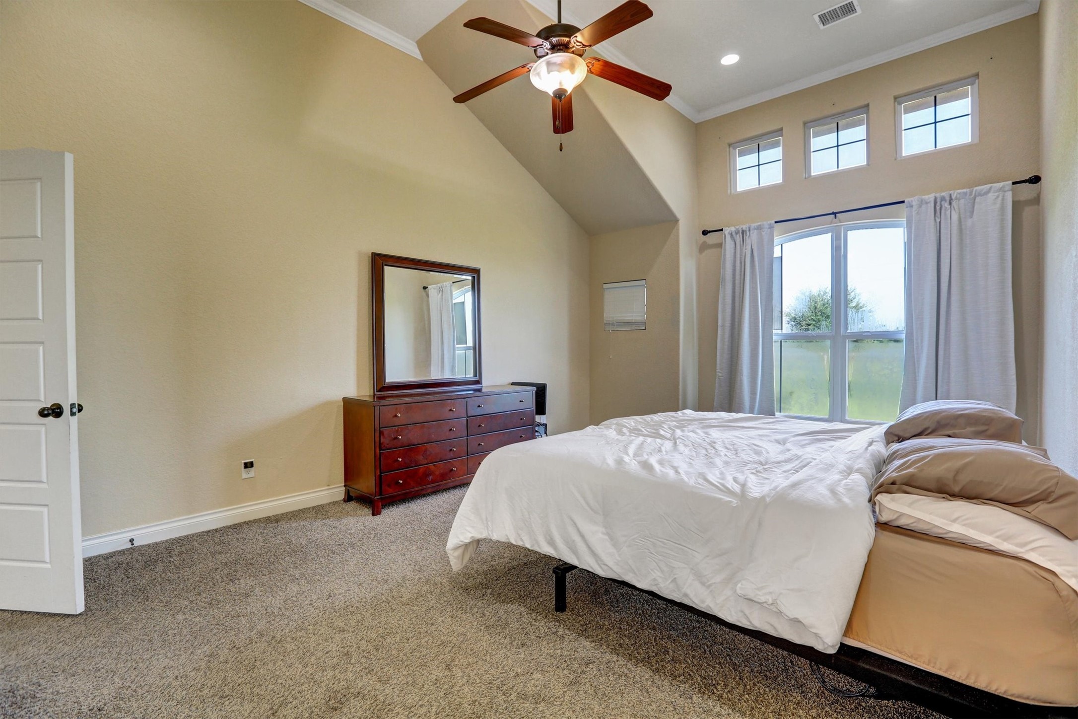 8131 Brinkmeyer Road Needville, TX 77461 - Photo 35 of 49 Spacious bedroom featuring vaulted ceilings, a large window with abundant natural light, and a ceiling fan for comfort.