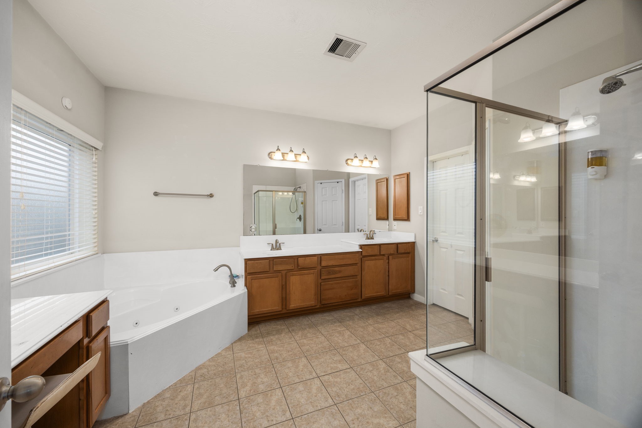 6719 Latchmore Lane Houston, TX 77049 - Photo 27 of 46 a large bathroom with a tub shower sink granite and a mirror
