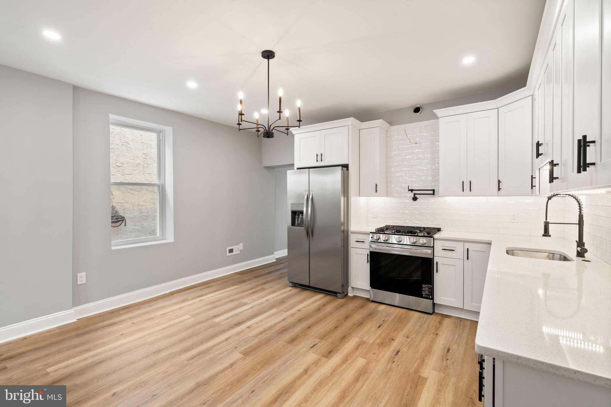 3464 Division Street Philadelphia, PA 19129 - Photo 13 of 40 a kitchen with stainless steel appliances granite countertop a refrigerator a sink dishwasher a stove and white countertops with wooden floor