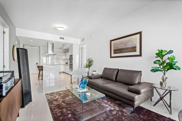 a living room with furniture potted plant and kitchen view