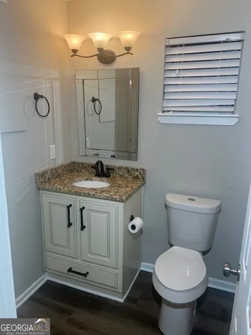 a bathroom with a granite countertop toilet sink and mirror
