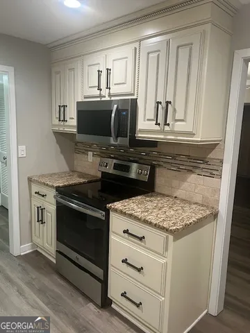 a kitchen with granite countertop white cabinets and black appliances