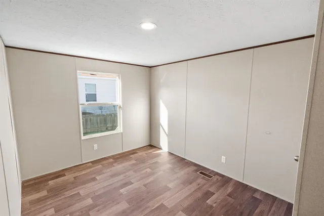 an empty room with wooden floor and windows with curtains