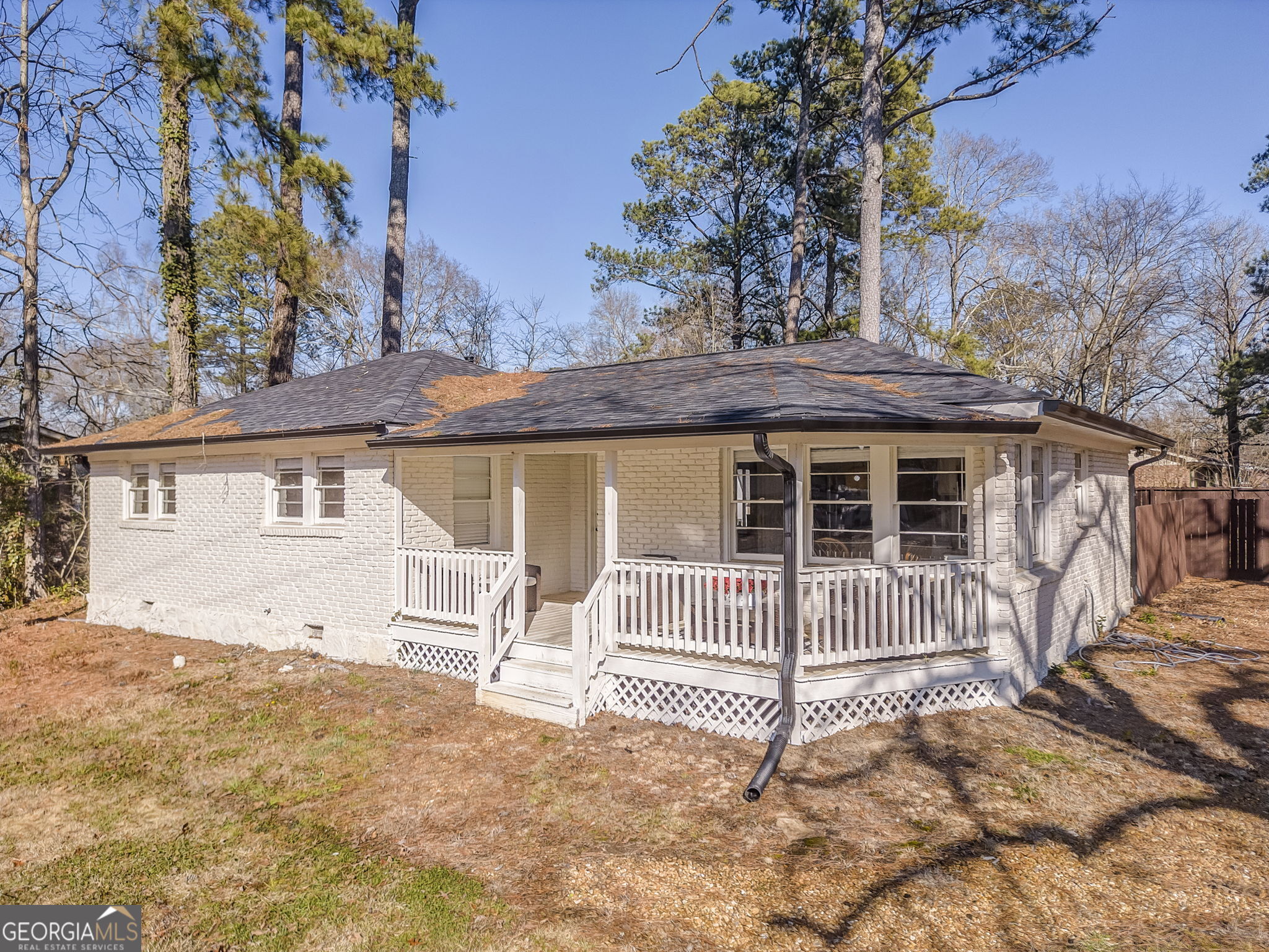 a view of a house with a wooden fence and a large tree