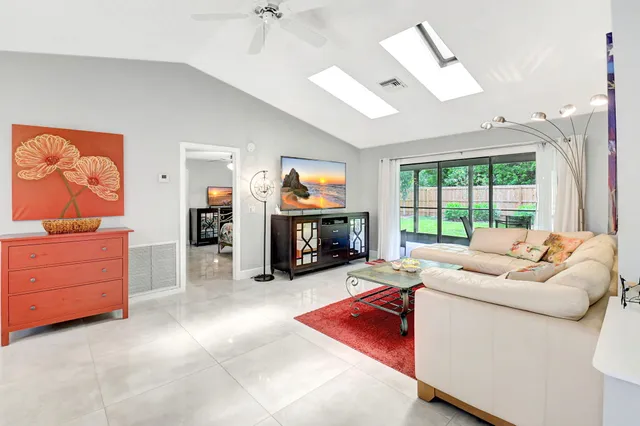 a living room with furniture a flat screen tv and a floor to ceiling window