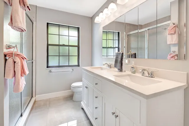 a bathroom with a double vanity sink toilet and a mirror