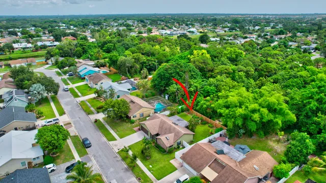 an aerial view of residential houses with outdoor space and trees all around