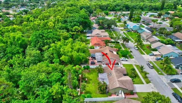 an aerial view of a house with a yard and a large tree