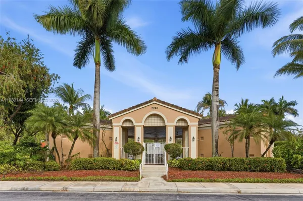 front view of a house with a yard and palm trees