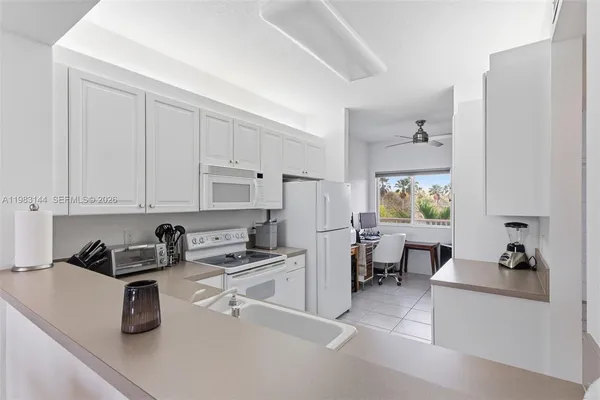 a kitchen with white cabinets and window