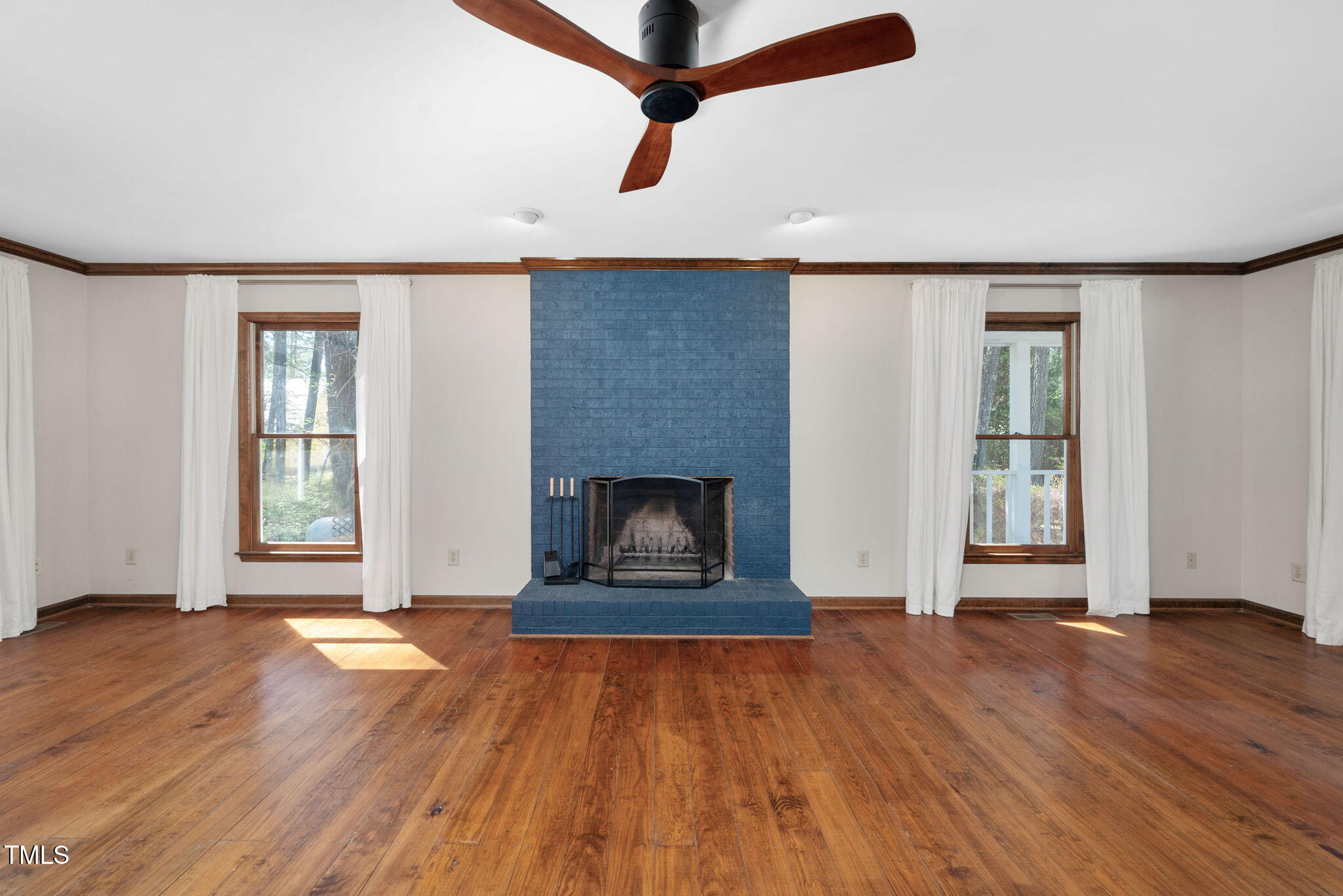 7917 Blaney Franks Road Apex, NC 27539 - Photo 6 of 50 an empty room with wooden floor a ceiling fan and windows
