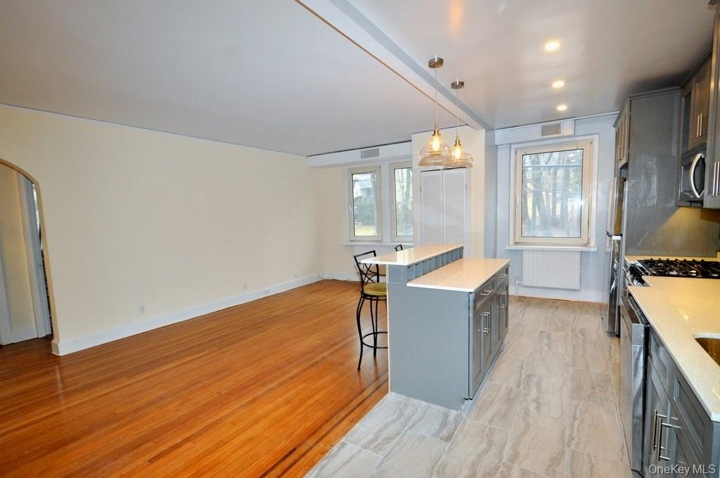 69 Harney Road, Unit 3A Scarsdale, NY 10583 - Photo 14 of 22 Renovated Kitchen with center Island, pendent lighting, Granite Counters, Stainless Steel Appliance including a dishwasher, range, microwave and refrigerator. The wall separating the eat-in-kitchen and living room have been removed and a center Island installed with electric and USB outlets installed to create an open concept.