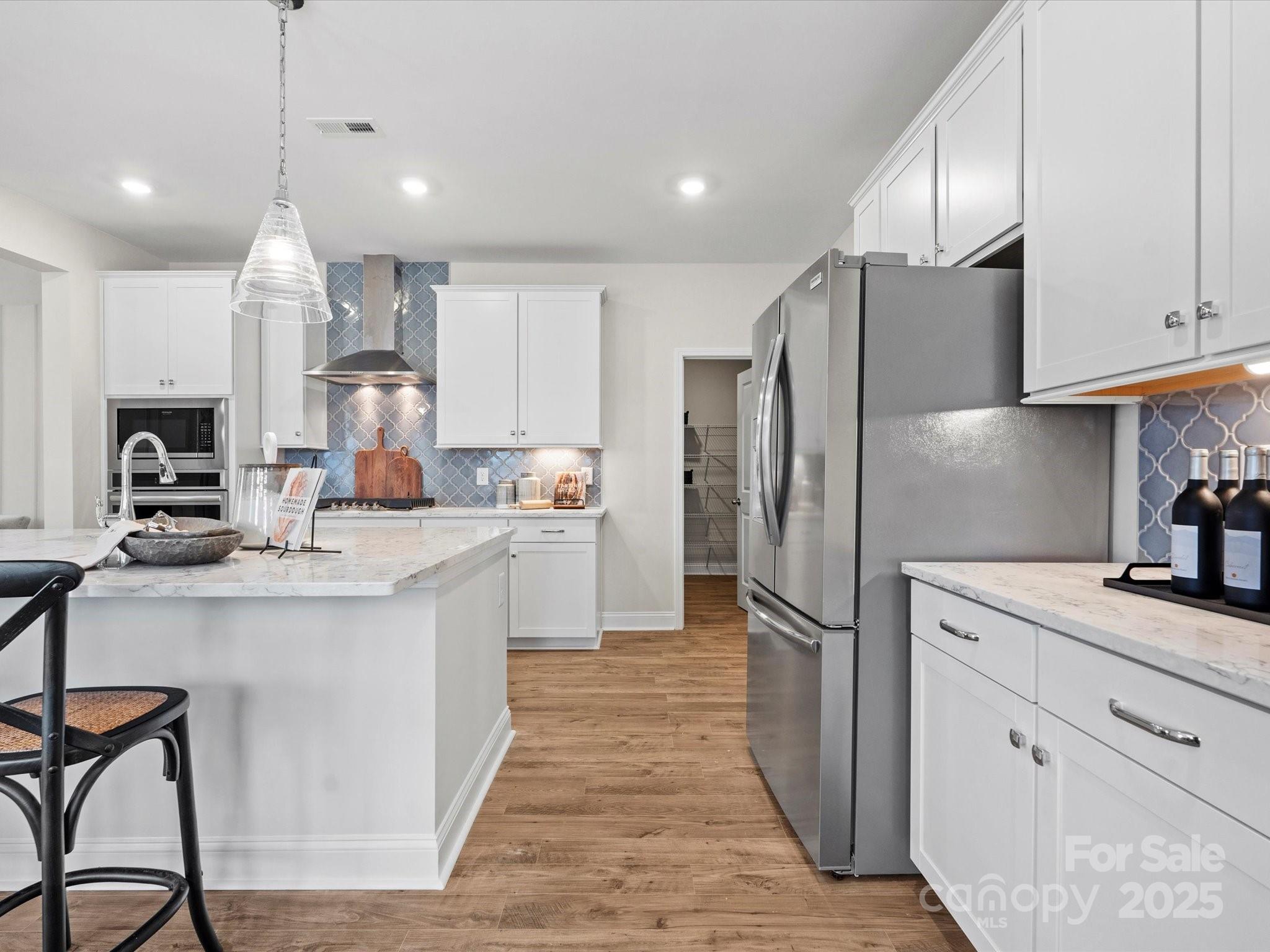 1016 Broken Spur Road Indian Trail, NC 28079 - Photo 6 of 19 a kitchen with kitchen island white cabinets and stainless steel appliances