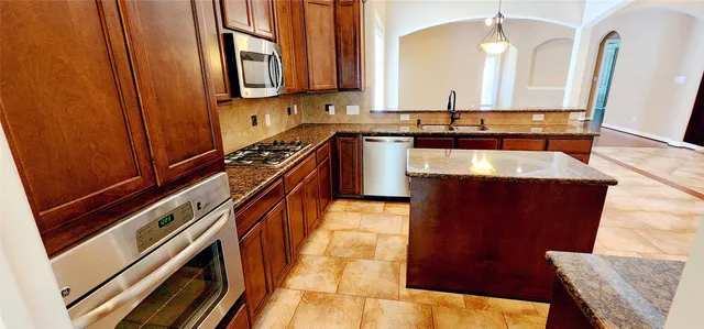 a kitchen with granite countertop a sink a stove and a microwave oven