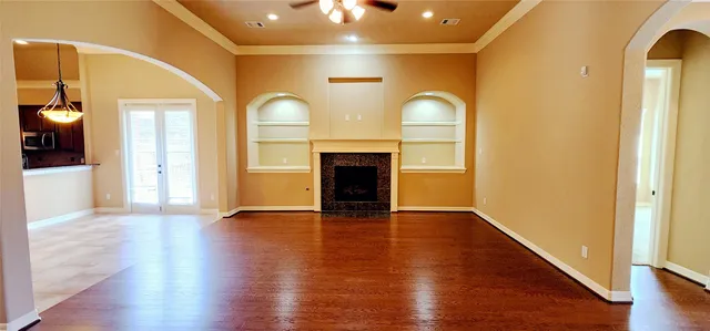 an empty room with wooden floor fireplace and windows