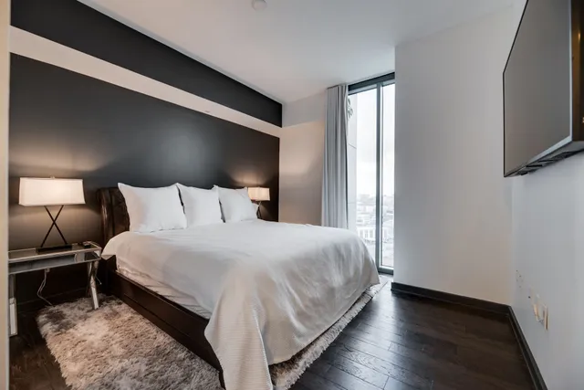 a bedroom with a bed and a flat tv screen on a dresser