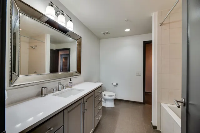 a bathroom with a double vanity sink a mirror and a toilet