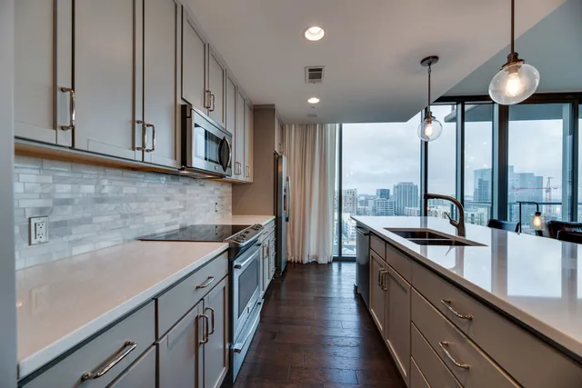 a kitchen with stainless steel appliances granite countertop a sink a stove and a wooden floors