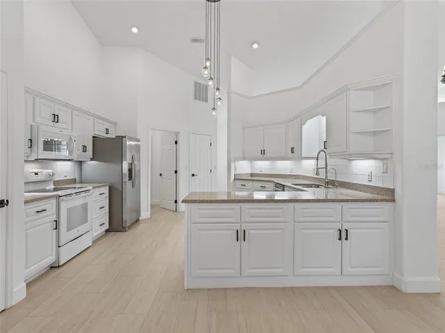 a large white kitchen with a lot of cabinets and stainless steel appliances
