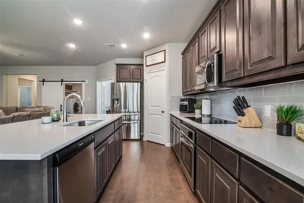 a kitchen with stainless steel appliances granite countertop a sink a stove and a refrigerator