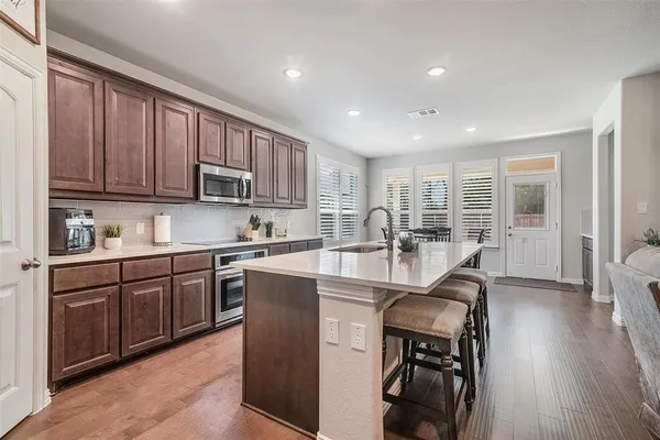 a kitchen with kitchen island granite countertop wooden floors and wooden cabinets