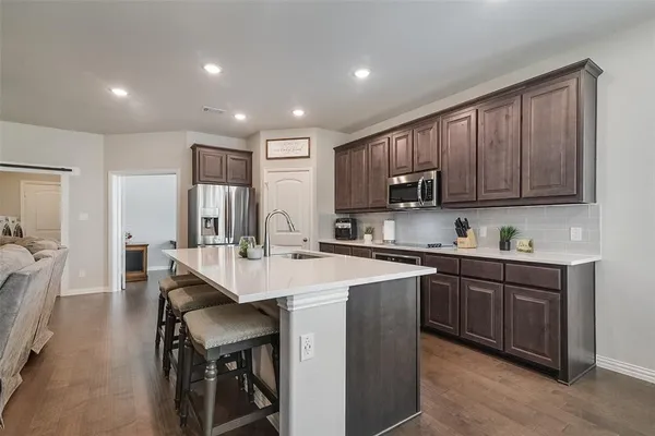 a kitchen with kitchen island granite countertop wooden cabinets a sink and white appliances