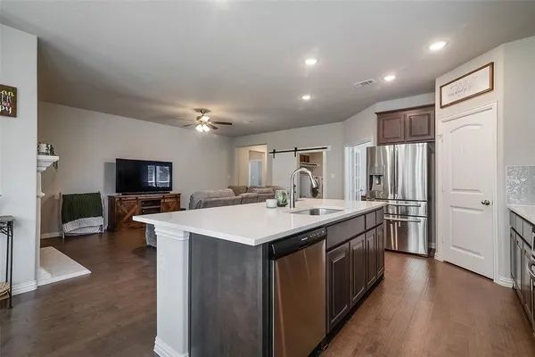 a large kitchen with a large counter top a sink stainless steel appliances and cabinets