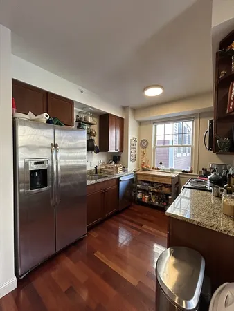 a kitchen with refrigerator a stove a sink dishwasher and wooden cabinets with wooden floor