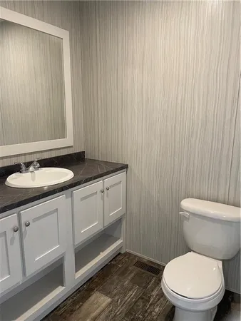 a bathroom with a granite countertop toilet a sink and mirror
