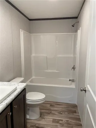 a bathroom with a granite countertop bathtub shower sink vanity and toilet