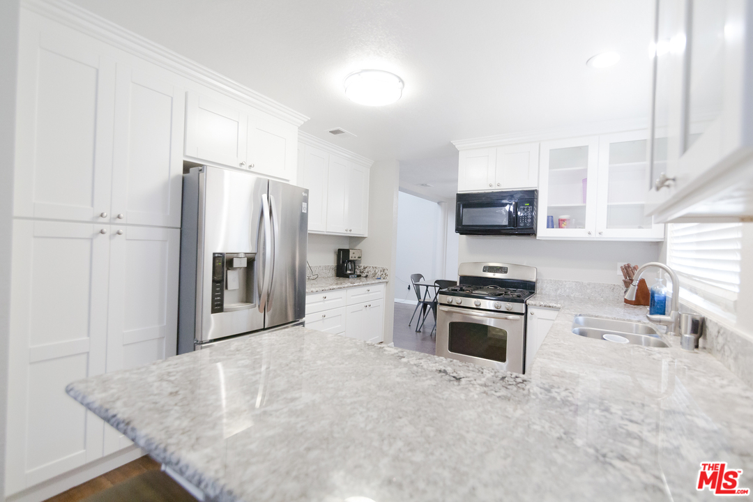 2985 North Chestnut Street Rialto, CA 92376 - Photo 12 of 30 a kitchen with stainless steel appliances granite countertop a stove a sink and a refrigerator