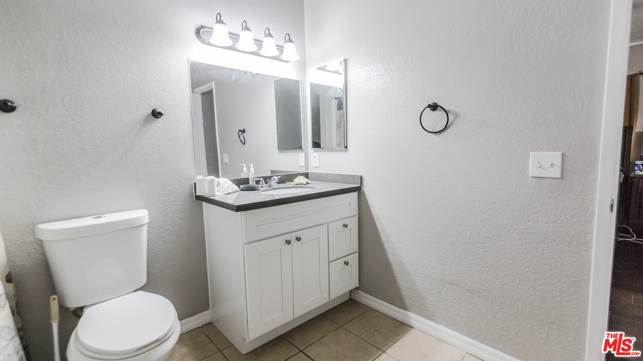 2985 North Chestnut Street Rialto, CA 92376 - Photo 16 of 30 a bathroom with a toilet a sink a mirror and vanity