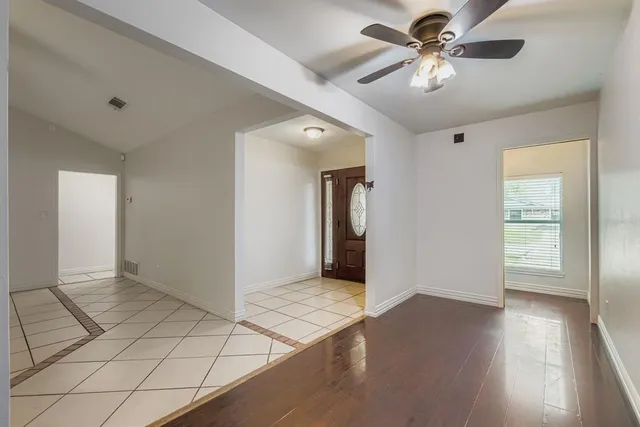 a view of an empty room with window and wooden floor