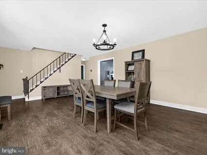 a dining room with wooden floor a chandelier a wooden table and chairs