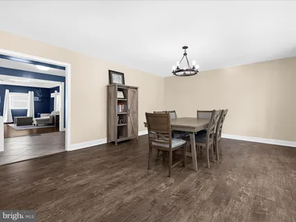 a dining room with wooden floor a chandelier a wooden table and chairs