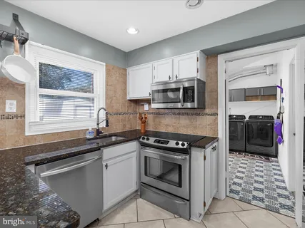 a kitchen with granite countertop a stove sink and microwave