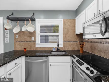 a kitchen with granite countertop a sink a stove and cabinets