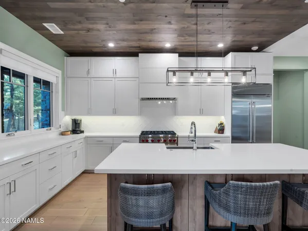a kitchen with stainless steel appliances granite countertop a sink a stove and chairs