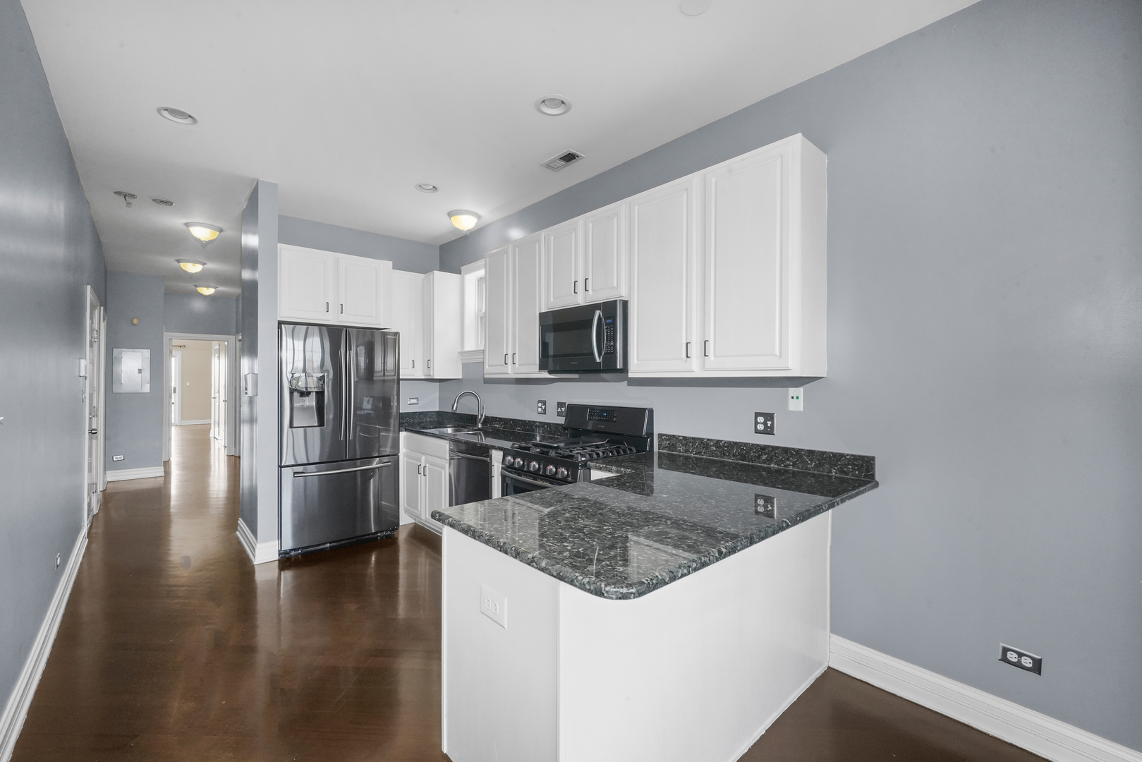 2503 West Harrison Street, Unit 4 Chicago, IL 60612 - Photo 10 of 31 a kitchen with stainless steel appliances granite countertop a refrigerator a stove a sink a microwave oven with white cabinets and wooden floor