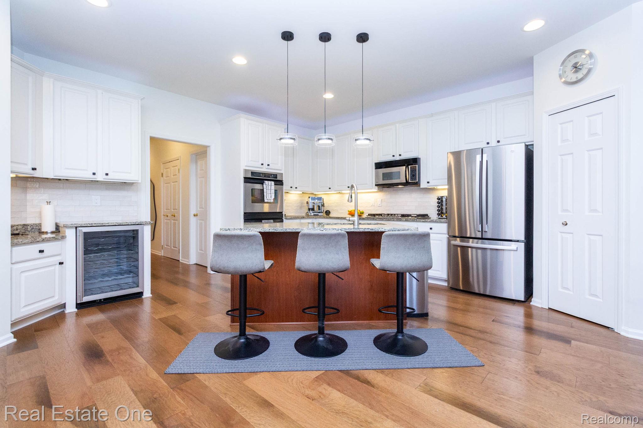 3585 Winding Brk Circle, Unit 89 Rochester, MI 48309 - Photo 15 of 59 Kitchen featuring light stone countertops, beverage cooler, stainless steel appliances, decorative light fixtures, and a center island with sink