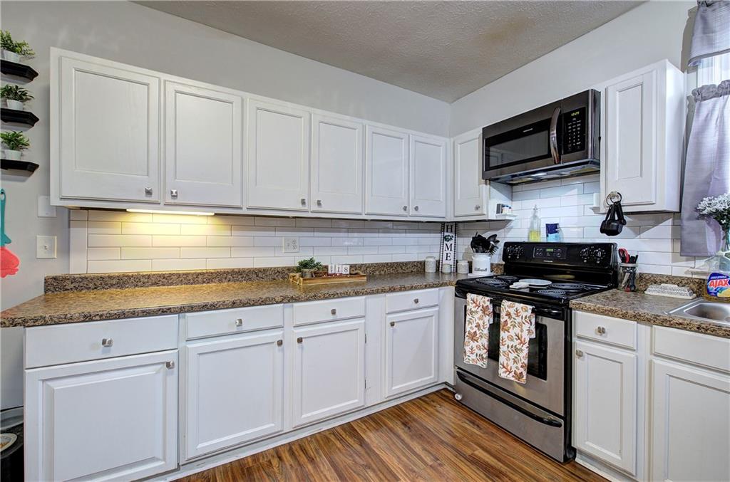 413 Calhoun Avenue Northeast Rome, GA 30161 - Photo 11 of 27 a kitchen with stainless steel appliances granite countertop a stove a sink and white cabinets