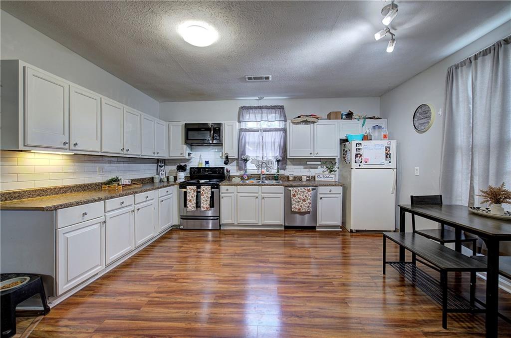 413 Calhoun Avenue Northeast Rome, GA 30161 - Photo 8 of 27 a kitchen with kitchen island granite countertop wooden floors stainless steel appliances and white cabinets