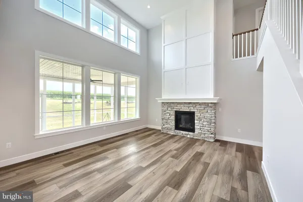 an empty room with wooden floor fireplace and windows